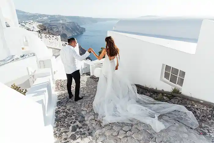 Newly wedded couple walking down cobbled steps,Santorini island, greece