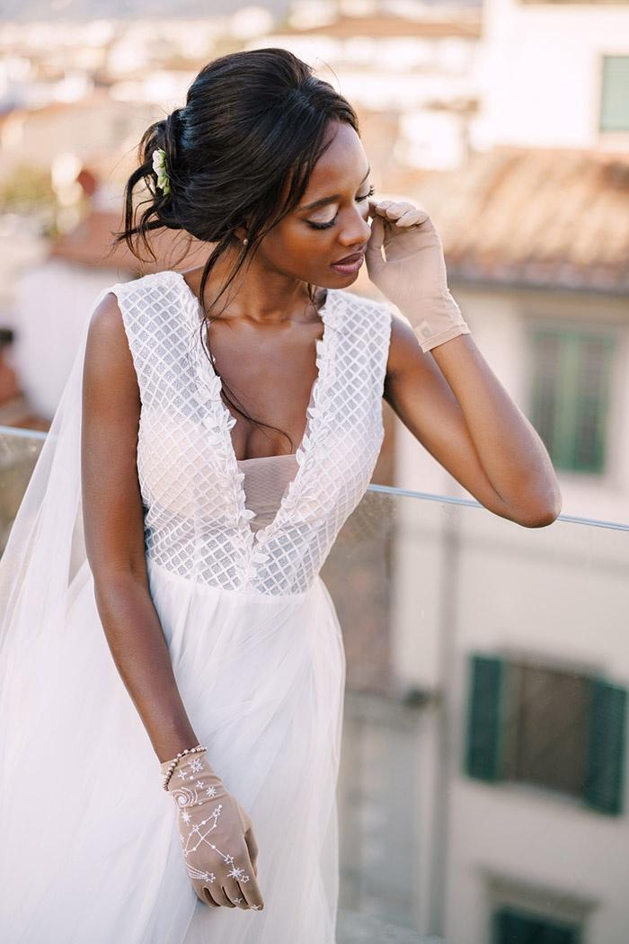 African American bride in a white wedding dress, touches her face with vintage wedding gloves, wedding in Florence, Italy