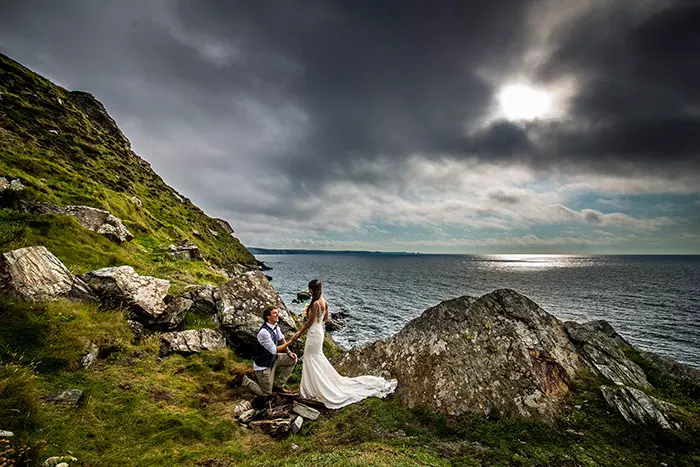 couple, future groom proposing to future bride on the coastpath overlooking Tregardock Beach, Cornwall, United Kingdom