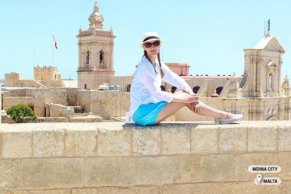 tourist sitting on wall, mdina city, malta