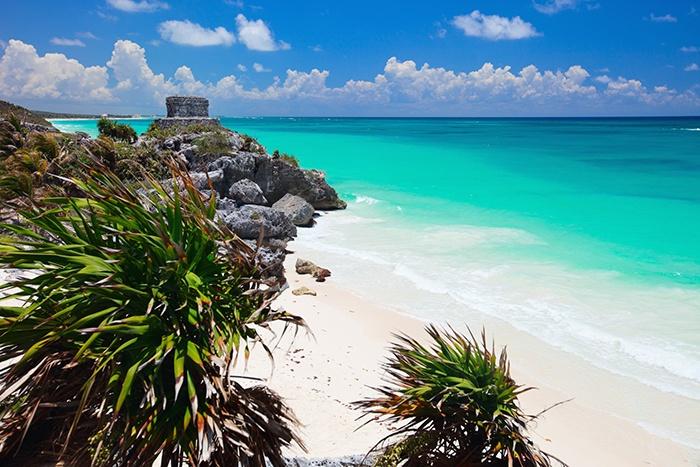 sandy golden beach in Tulum, Mexico with Mayan ruins in foreground 